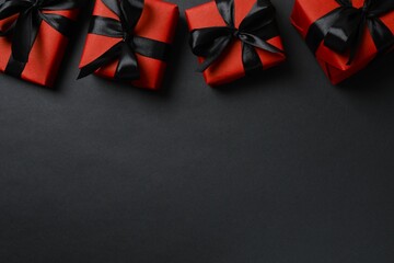 Black Friday concept. Red gift boxes tied with ribbons,  on a dark backdrop, providing space for your message or promotion
