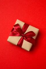 A wrapped gift with a red ribbon on red background conveying a festive greeting, perfect for New Year and Christmas greetings