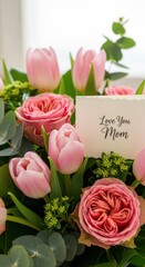 Close-up bouquet of pink tulips and roses with handwritten “Love You Mom” greeting card, bright background