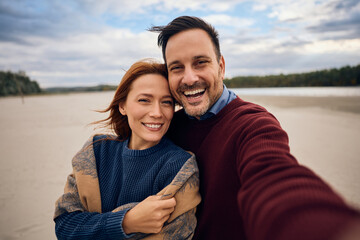 Obraz premium Happy couple taking selfie in autumn and looking at camera.