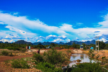Scenic Rural Landscape with Distant Mountains, Pond, and Bright Blue Sky