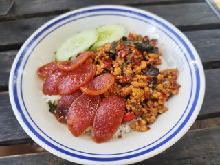 Stir-fried minced pork with holy basil served with fried Chinese sausage and cucumber