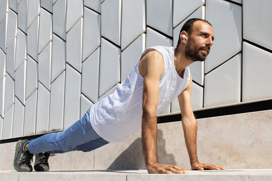 Runner stretches with plank exercise outdoors in morning at Lisbon Maat