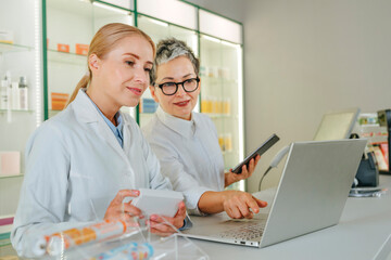 Pharmacists consulting and using laptop at pharmacy counter
