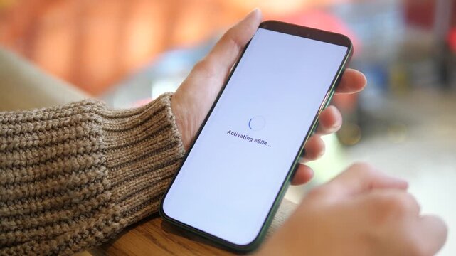 A womans hands in a shopping mall complete an eSIM activation process through a mobile application, reviewing terms and pricing before confirming the purchase and receiving successful setup