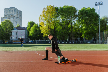 A man sits doing lunges on a running track