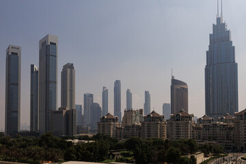 Fototapeta premium Majestic Dubai skyline view on a hazy day, showing soaring modern skyscrapers behind traditional Arabian-style residential architecture. High quality photo