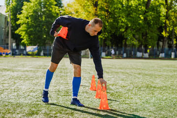 A man puts training cones on the field