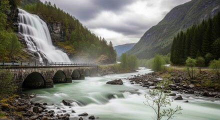 Dramatic waterfall cascades over a stone bridge into a rushing river, surrounded by lush green mountains under a cloudy sky