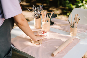 Clay rolling with a pin shapes material for pottery and ceramic art. Rolling pin flattening clay on table. Clay is rolled flat with precision, setting the stage for ceramic art.