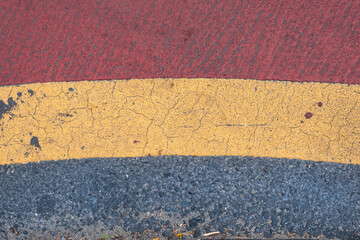 Grey tarmac road texture with red and yellow paint