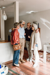A group of four friends stand and talk while the men hug the women