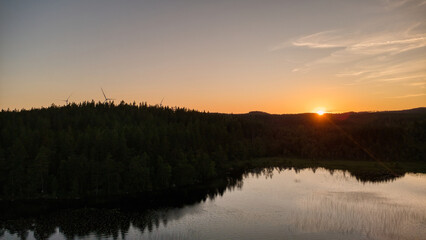 Sunset at the lake with reflection and forest, peaceful evening atmosphere