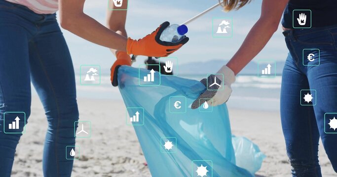 Volunteers wearing gloves collecting litter on beach, placing plastic bottle into blue trash bag - Powered by Adobe