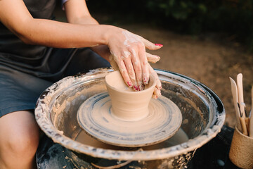 Potter shaping clay bowl on a wheel. Clay spins gently under hands as potter forms bowl. Clay molding on the wheel highlights pottery artistry and skill.