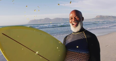 Standing surfer in wetsuit top, holding yellow surfboard on beach at ocean's edge, copy space
