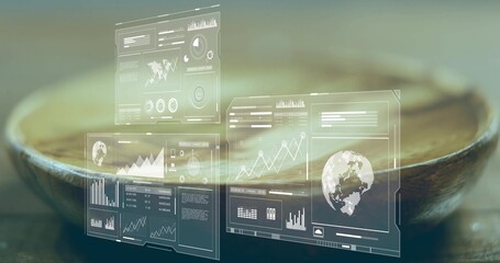 Translucent digital interface panels showing data charts and world map above wooden bowl in studio