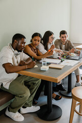 A female worker watches as a male worker writes on a sticky note while a male and female worker...
