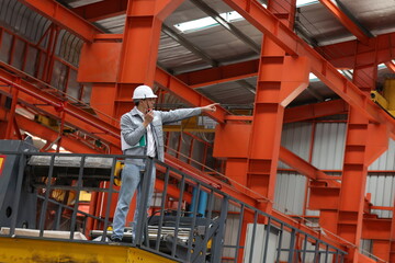Industrial Engineer in Hard Hats Work at the Heavy Industry Metal Sheet Manufacturing Factory. Factory worker indoors in metal sheet factory. Man working in an industrial factory. 