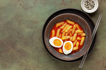 Tteokbokki with eggs in gray bowl . Tteok-bokki is a korean cuisine dish with rice cakes. Asian food. Top view. Copy space