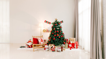 Bright minimalist living room decorated for Christmas with a trimmed tree, red and white ornaments, wrapped gifts, cozy chair, and natural light from large windows.