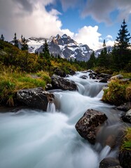Stream flows from mountains under a partly cloudy sky