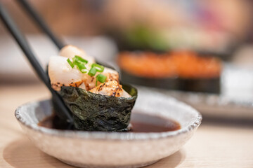 Sushi in chopsticks dipping with soy sauce