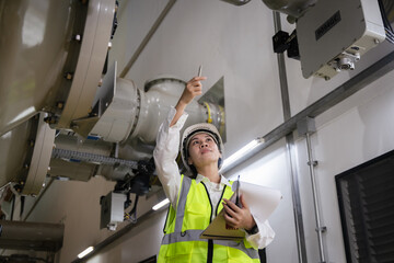 inspecting high-voltage gas-insulated switchgear (GIS), Female engineer in safety helmet, reflective vest inside a power plant, taking notes on clipboard, symbol of industrial safety, professionalism