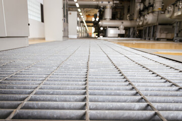 Close-up view of industrial steel floor grating inside a power plant facility, designed for safety, durability, and ventilation in heavy-duty environments with high electrical equipment