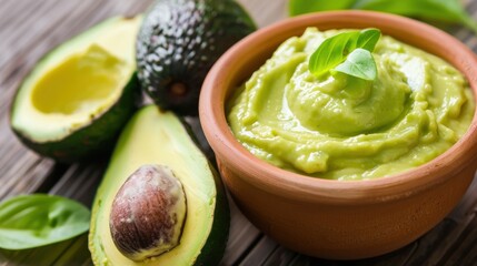 Creamy Avocado Dip in a Clay Bowl with Fresh Avocados on Wooden Surface and Green Basil Leaves