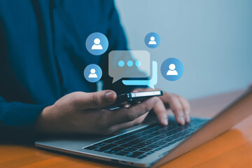 Businessman using smartphone and laptop with chat icons, concept of online communication, social media marketing, customer support, digital connection, and business messaging technology.