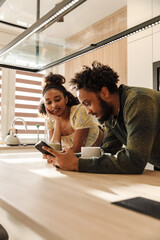 Obraz premium Male and female musicians are standing and leaning on the table while looking at the phone he is holding