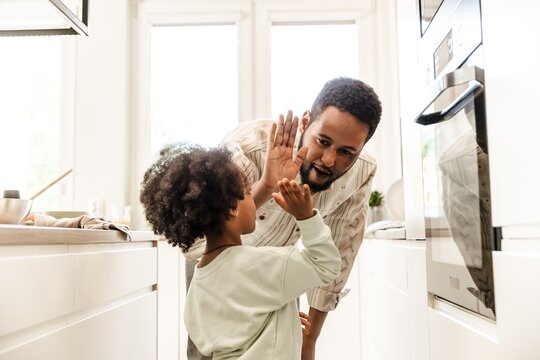 The father talks and gives a high five to his daughter who is standing next to him - Powered by Adobe