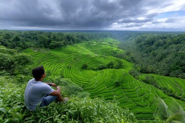 Man enjoying a scenic view of lush green rice terraces in Ubud during a cloudy afternoon
