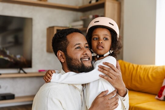 A father and his daughter in a helmet are hugging and looking ahead - Powered by Adobe