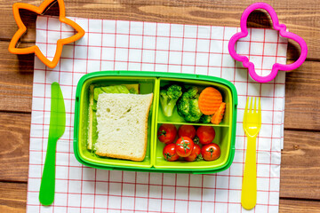 green lunch box for kid on wooden background top view