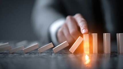 A hand stops the domino effect, symbolizing risk management and intervention. Strategy to prevent cascade of failures and protect stability.