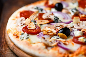Pizza with chorizo ​​sausage, mozzarella cheese, and black olives. Rustic wooden background. Soft focus.	