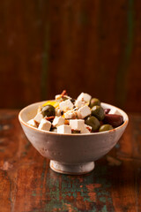 Green and kalamata olives and feta cheese on rustic wooden background. Soft focus.	