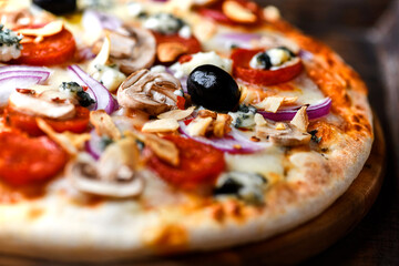 Pizza with chorizo ​​sausage, mozzarella cheese, and black olives. Rustic wooden background. Soft focus.	