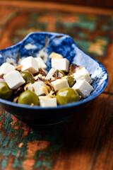 Green and kalamata olives and feta cheese on rustic wooden background. Soft focus.	