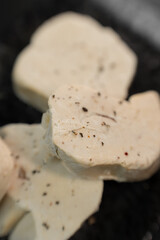 A striking close-up of luxurious French foie gras, beautifully presented on a sleek black marble plate, emphasizing the gourmet texture and elegant contrast
