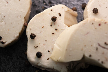 Seared foie gras delicacy, generously seasoned with coarse black pepper, creating a visually striking and rich texture contrast, ready for fine dining enjoyment