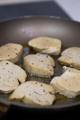 Seared foie gras sizzling in a hot frying pan with rendered fat, creating a golden-brown crust for a classic French gourmet cooking process