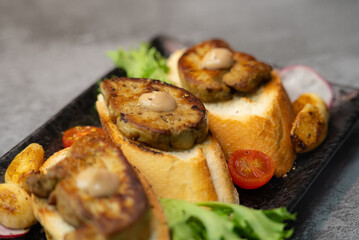 Elegant seared foie gras on toasted bread, served with a side of savory roasted vegetables including vibrant tomatoes and garlic
