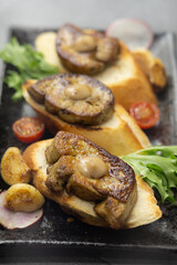 Delicious seared foie gras on toasted bread, garnished with savory roasted vegetables, including...