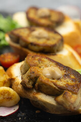 Delicious seared foie gras on toasted bread, garnished with savory roasted vegetables, including tomatoes, and aromatic garlic