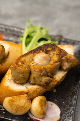 Elegant seared foie gras on toasted bread, served with a side of savory roasted vegetables including vibrant tomatoes and garlic