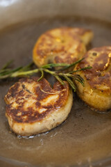 Sizzling pan-seared foie gras with fresh thyme sprigs in a hot skillet, creating a rich, aromatic French gourmet delicacy