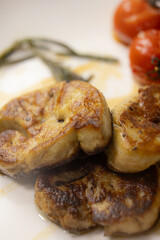 Elegant Gourmet Dish: Succulent Seared Foie Gras with Roasted Tomato and Thyme, Served with a Rich, Exclusive Specialty Sauce on a White Plate